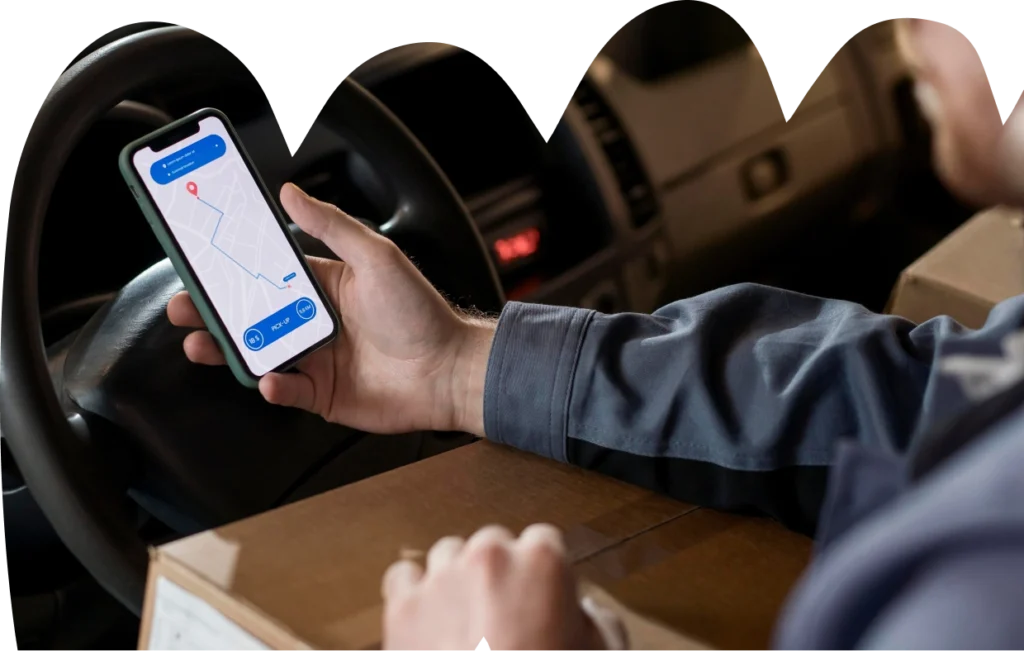 Een persoon in een voertuig houdt een smartphone vast waarop een kaartapp te zien is. Op zijn schoot ligt een bruin pakket, wat de indruk wekt van navigatie en bezorging.